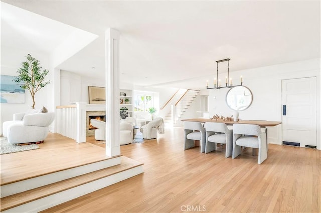 dining area with built in shelves, light hardwood / wood-style flooring, and a chandelier