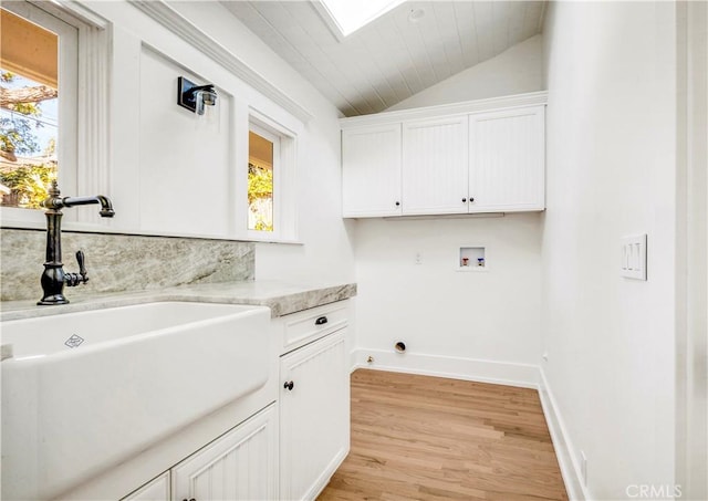 laundry room featuring cabinets, a skylight, washer hookup, sink, and light hardwood / wood-style flooring