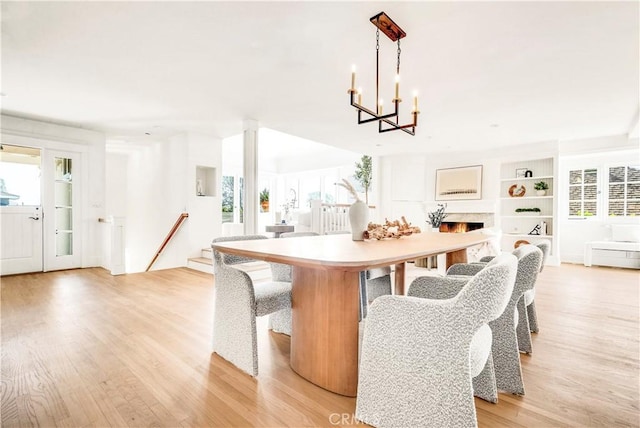 dining area with built in shelves, a notable chandelier, and light hardwood / wood-style floors