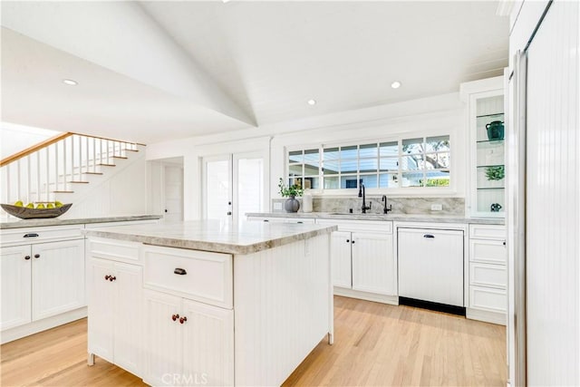 kitchen featuring a kitchen island, sink, white cabinetry, light wood-type flooring, and dishwashing machine