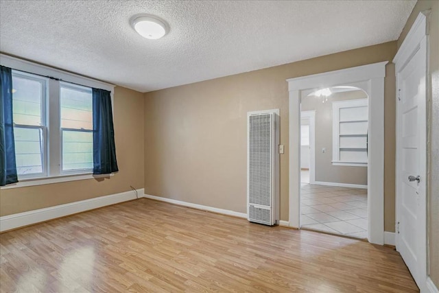 spare room with a textured ceiling and light hardwood / wood-style flooring