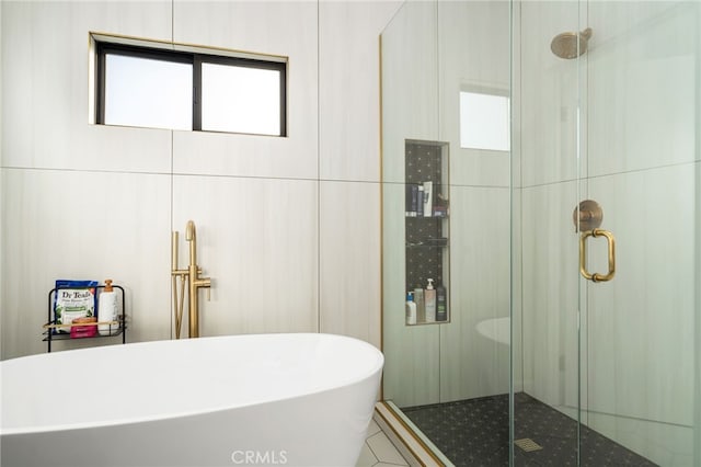 bathroom featuring plus walk in shower and tile walls