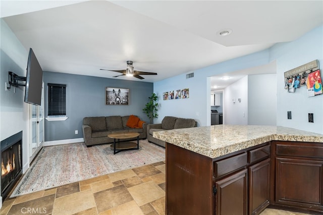 kitchen with ceiling fan, washer / dryer, and dark brown cabinetry