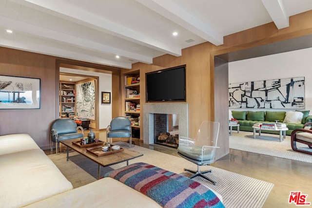 living room with a multi sided fireplace, hardwood / wood-style flooring, built in features, and beamed ceiling