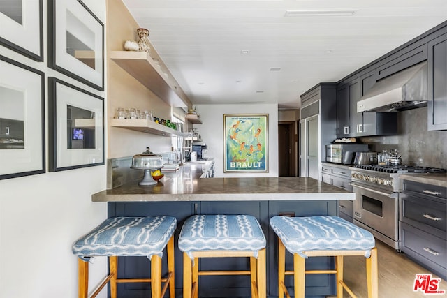 kitchen featuring exhaust hood, a breakfast bar area, stainless steel appliances, and hardwood / wood-style flooring