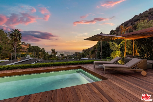 pool at dusk featuring a wooden deck