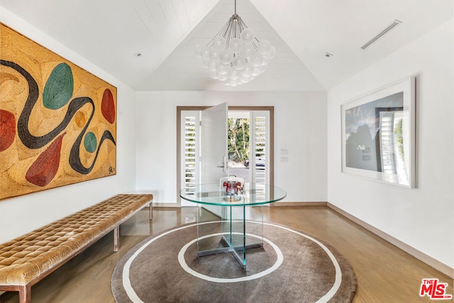 dining space featuring hardwood / wood-style floors, an inviting chandelier, and vaulted ceiling