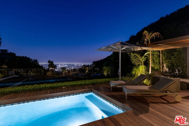 pool at dusk featuring a wooden deck