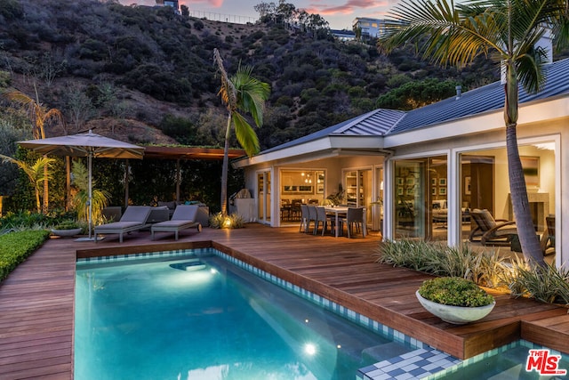 pool at dusk featuring a deck