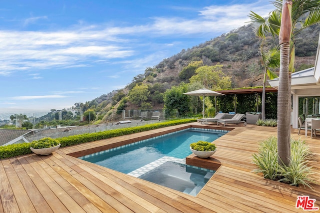 view of swimming pool with an outdoor living space and a deck with mountain view