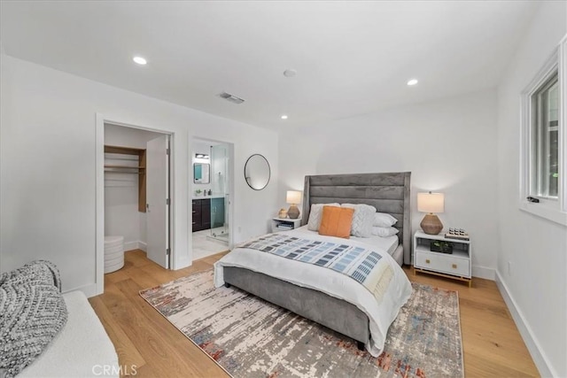 bedroom with connected bathroom, a closet, a walk in closet, and light wood-type flooring