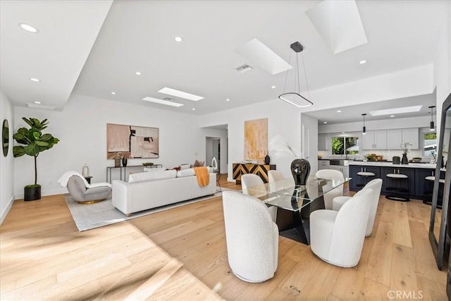 living room featuring light hardwood / wood-style flooring and a skylight