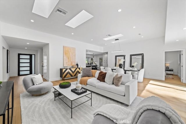 living room featuring a skylight and light hardwood / wood-style flooring