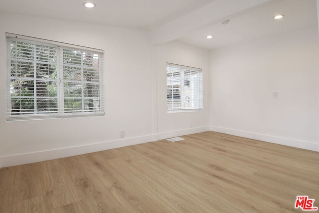 spare room with light hardwood / wood-style floors and beamed ceiling