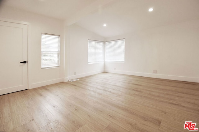 unfurnished room featuring light hardwood / wood-style floors and lofted ceiling with beams