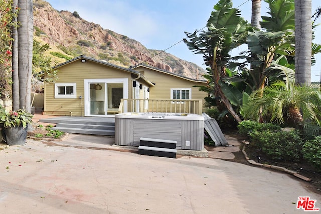 exterior space with a hot tub, a deck with mountain view, and a patio