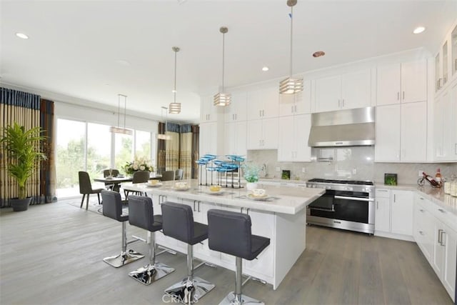 kitchen featuring light stone countertops, white cabinetry, high end stove, and a kitchen island