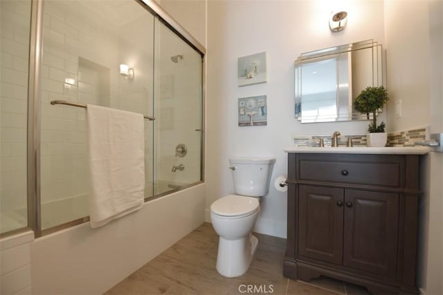 full bathroom featuring toilet, vanity, and shower / bath combination with glass door