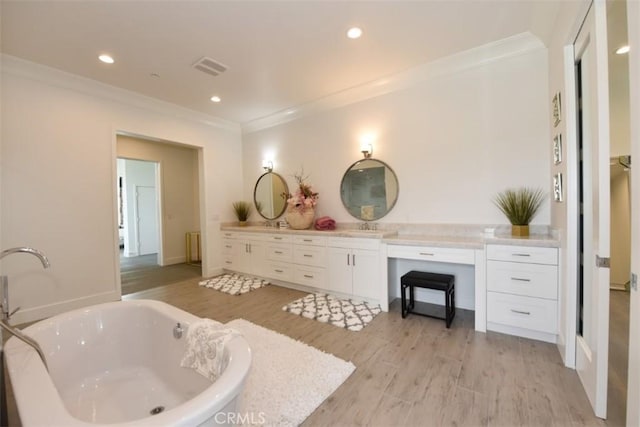 bathroom featuring hardwood / wood-style floors, vanity, crown molding, and a bathing tub