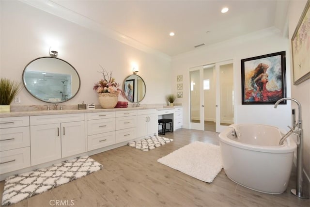 bathroom featuring hardwood / wood-style flooring, a bathtub, vanity, and crown molding