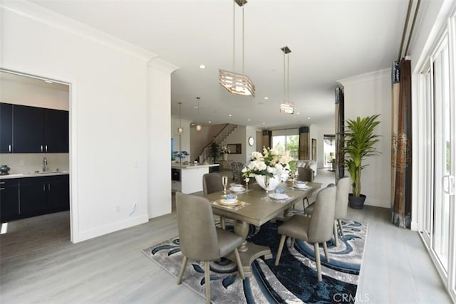 dining room with light wood-type flooring, sink, and crown molding