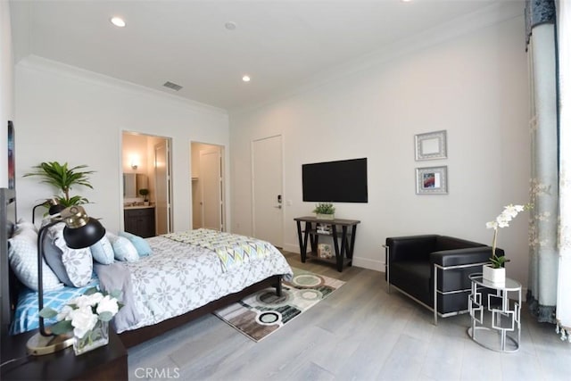 bedroom with crown molding, connected bathroom, and hardwood / wood-style flooring