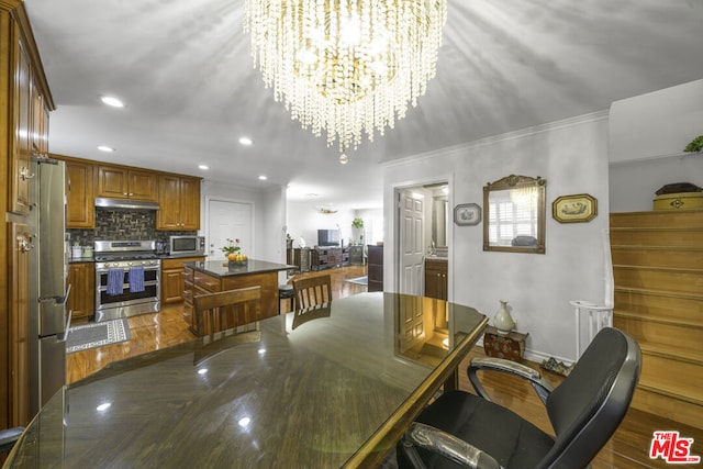 interior space with a center island, wood-type flooring, stainless steel appliances, tasteful backsplash, and an inviting chandelier