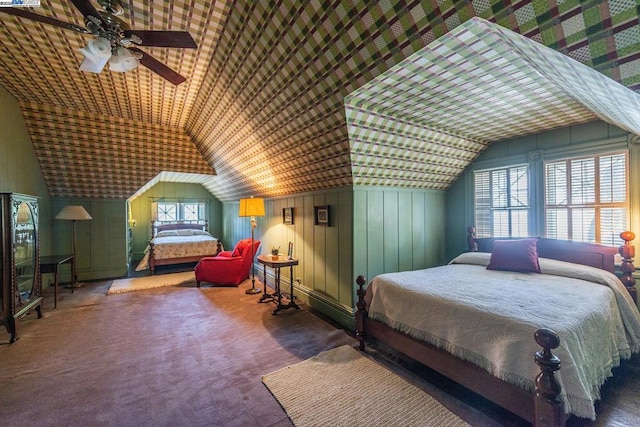 bedroom featuring ceiling fan, vaulted ceiling, wood walls, and dark carpet