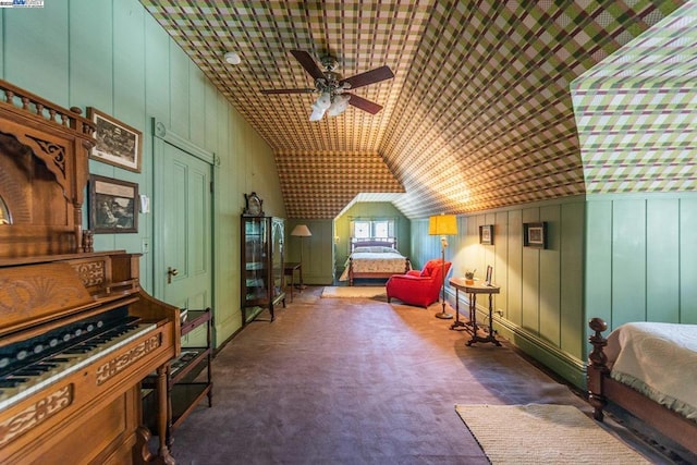 interior space featuring vaulted ceiling, wood walls, dark carpet, and ceiling fan