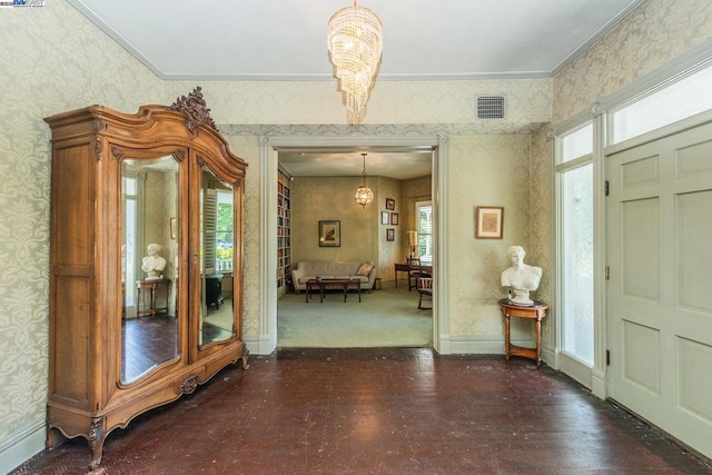 foyer entrance featuring a healthy amount of sunlight, crown molding, and a chandelier