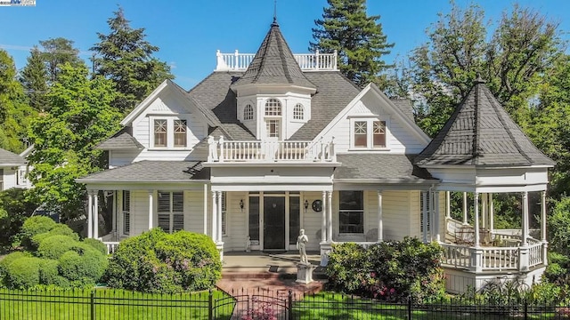 rear view of property featuring covered porch and a balcony