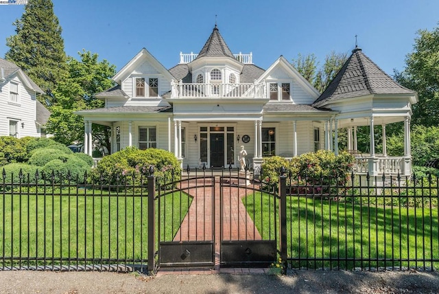 victorian house featuring a front yard, a porch, and a balcony