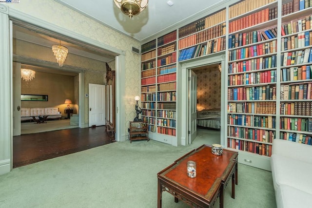 living area featuring carpet floors, crown molding, and a chandelier