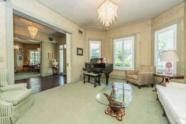 living area featuring a healthy amount of sunlight, crown molding, and a notable chandelier