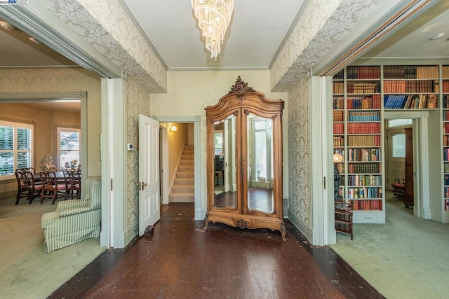 interior space featuring a notable chandelier, crown molding, and dark colored carpet