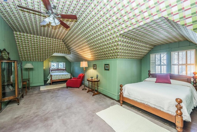 carpeted bedroom with ceiling fan, lofted ceiling, and wooden walls