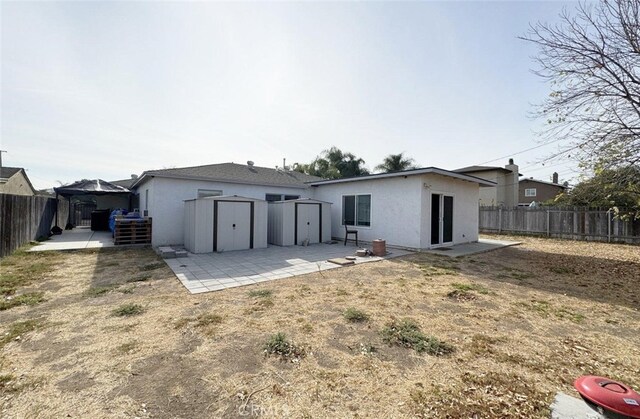 rear view of property featuring a patio area and a storage shed