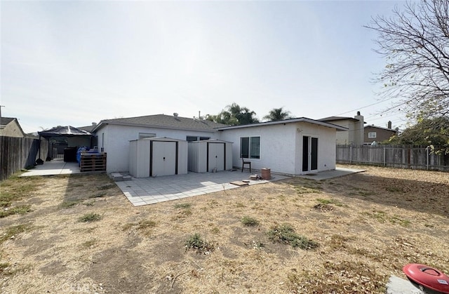 rear view of property featuring a storage unit and a patio area