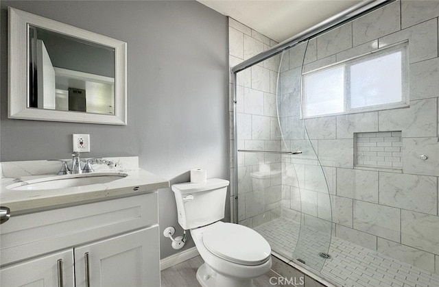 bathroom with a shower with shower door, toilet, and vanity