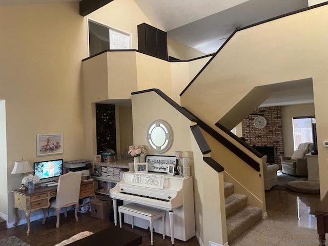 stairway featuring a towering ceiling and a brick fireplace