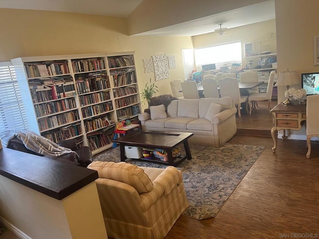 living room featuring dark wood-type flooring and vaulted ceiling