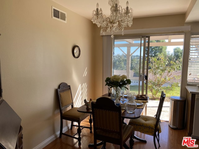 dining space with wood-type flooring and an inviting chandelier