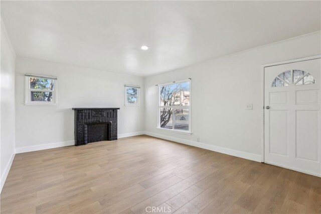 unfurnished living room with a brick fireplace and light hardwood / wood-style floors