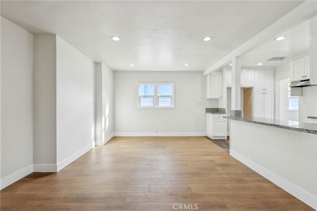 kitchen with white cabinetry, stone countertops, and light wood-type flooring