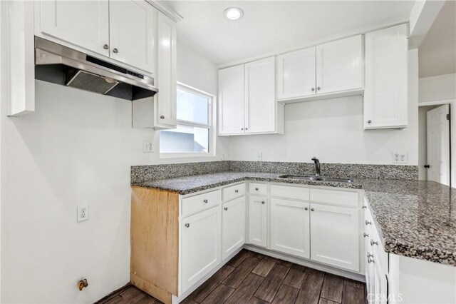 kitchen featuring white cabinets, dark stone counters, and sink