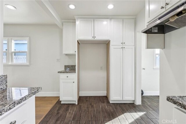 kitchen with dark stone counters and white cabinetry