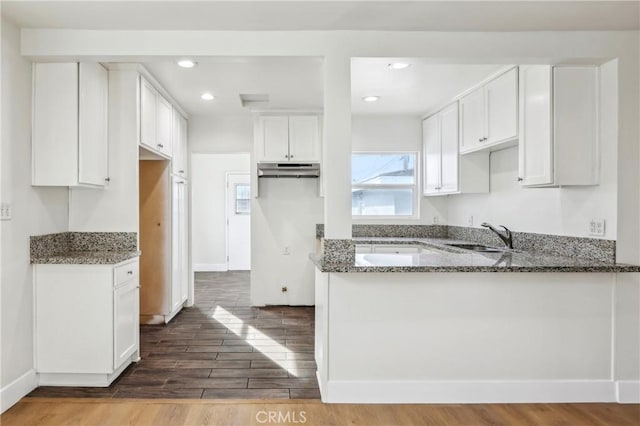 kitchen with sink, white cabinetry, dark stone counters, and dark hardwood / wood-style floors