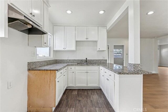 kitchen with light stone counters, kitchen peninsula, and white cabinetry