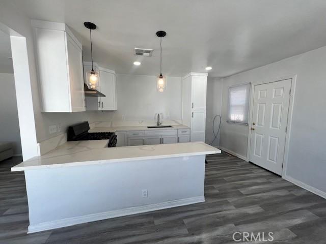 kitchen with kitchen peninsula, black range, white cabinets, and sink