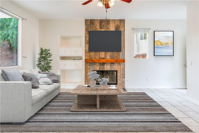 living room featuring a fireplace, ceiling fan, and light tile patterned flooring